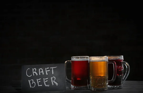 与不同种类的工艺啤酒在深色背景上的玻璃杯子 — 图库照片