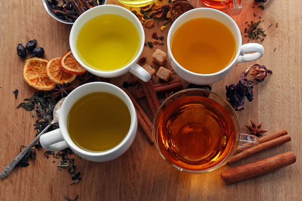 Tazze con diversi tipi di tè e ingredienti in tavola — Foto Stock