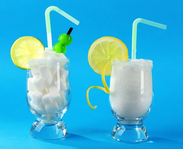 Glasses with granulated, lump sugar, cocktail straws, cherries and citrus slices on blue background — Stock Photo, Image