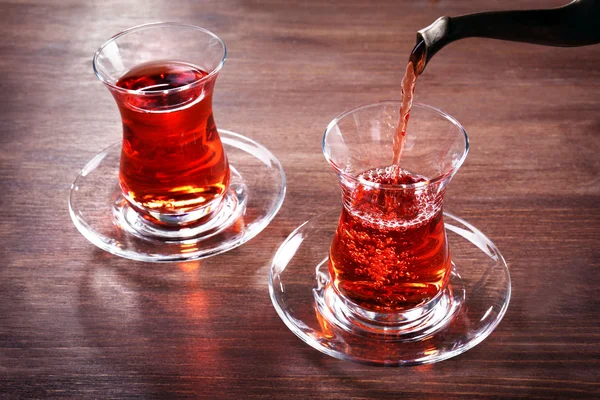 Pouring black tea into glass cups on wooden table — Stock Photo, Image