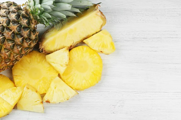 Snijden van verse ananas op houten achtergrond — Stockfoto