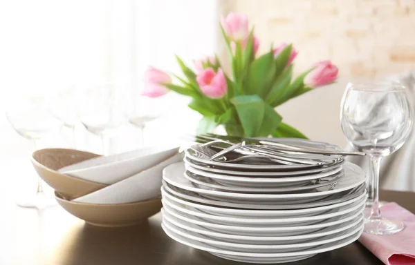 La pila de los platos, los cubiertos con el ramo de los tulipanes a la mesa . —  Fotos de Stock