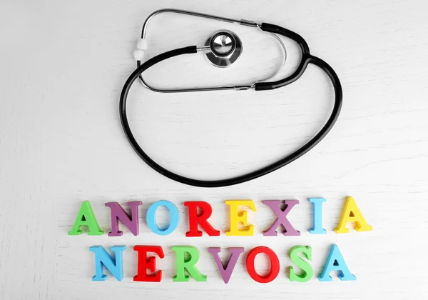 Anorexia nerviosa palabras coloridas y estetoscopio sobre fondo blanco . — Foto de Stock