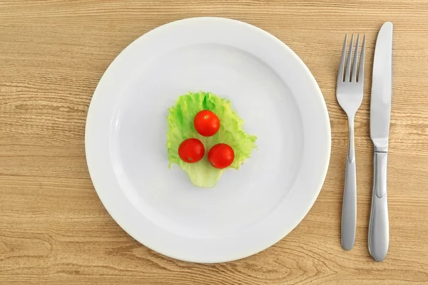 Witte plaat met salade en cherry tomaten op houten achtergrond — Stockfoto