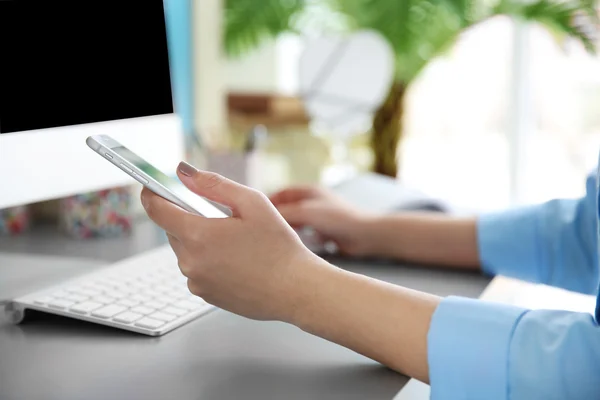 Frau arbeitet mit Smartphone und Computer in Innenräumen — Stockfoto