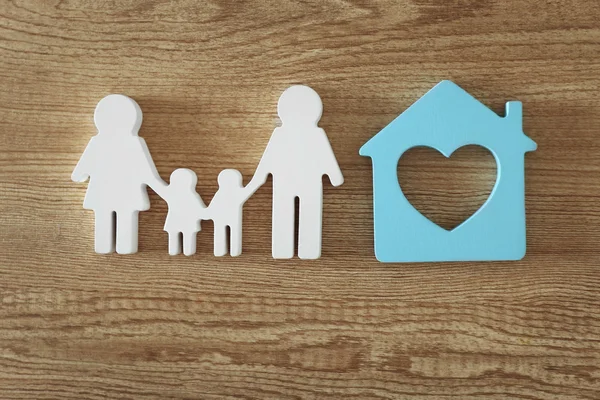 Aile figürü ahşap arka plan üzerinde bir ev ile — Stok fotoğraf