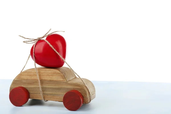 Wooden car with a red heart  tied to it over white background — Stock Photo, Image