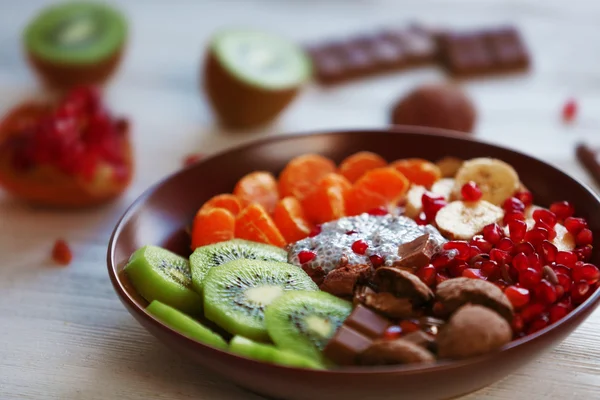 Чаша с шоколадным печеньем, нарезанные фрукты, семена чиа и граната на деревянном столе — стоковое фото