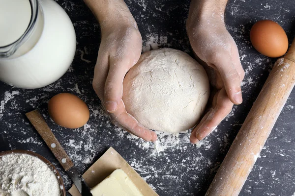 Mannelijke handen bedrijf rauwe deeg op keukentafel — Stockfoto