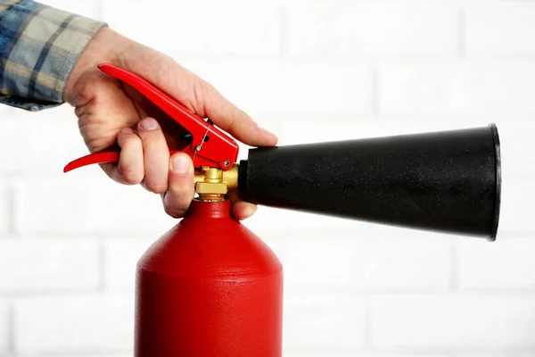 Hombre sosteniendo el extintor de incendios sobre fondo de pared de ladrillo blanco — Foto de Stock