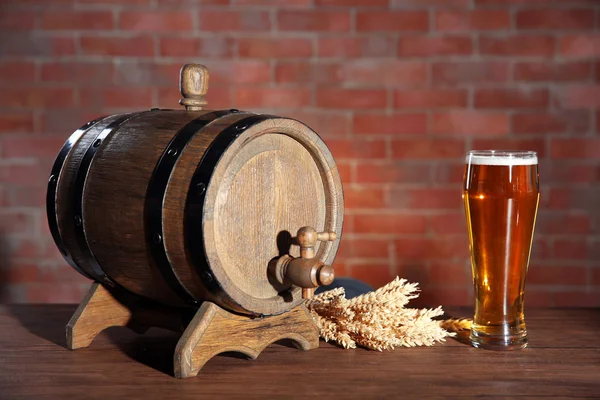Glass of light beer with wooden barrel and barley ears on brick wall background Stock Picture