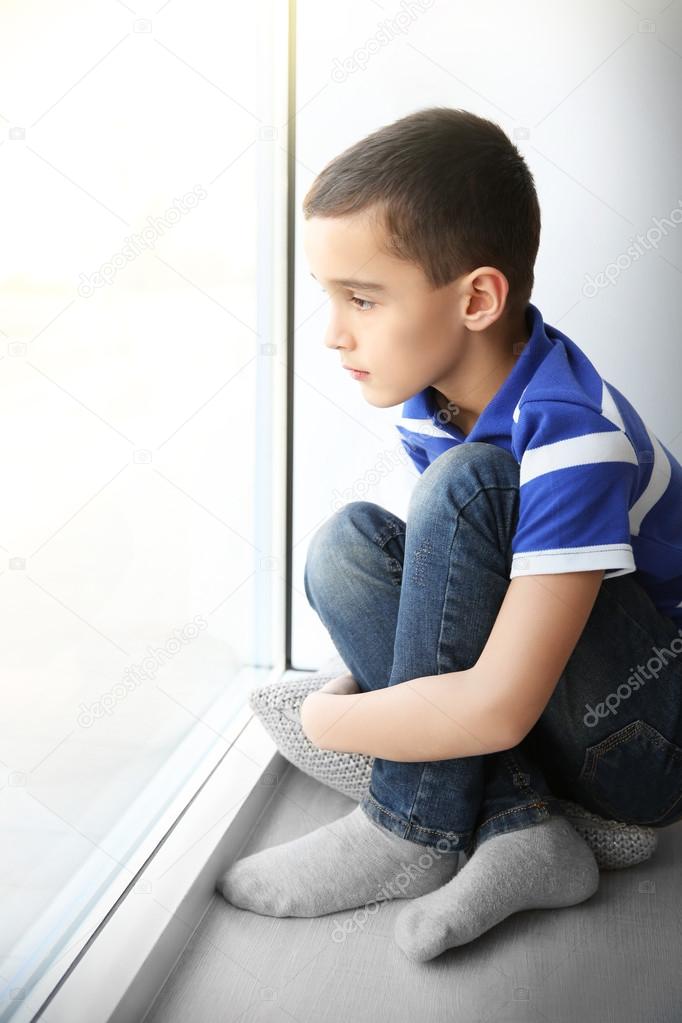 Single boy sitting on windowsill indoors