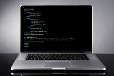Programlama kodu üstünde laptop 