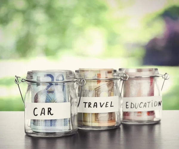 Jars for different needs full of banknotes — Stock Photo, Image