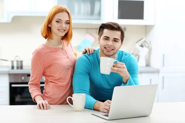 Pareja con taza de té usando portátil —  Fotos de Stock