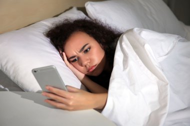 Uykulu kız yatakta cep telefonu ile