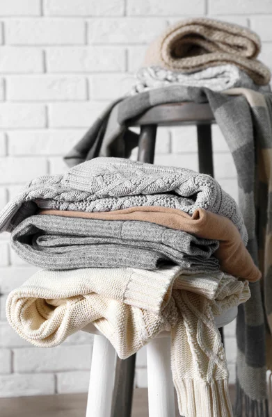 Piles of woolen clothes on wooden stools — Stock Photo, Image