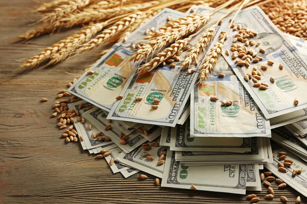 Dollar banknotes and wheat grains on wooden background. Agricultural income concept — Stock Photo, Image