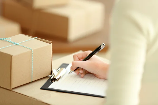 Woman signs papers among parcels — Stock Photo, Image