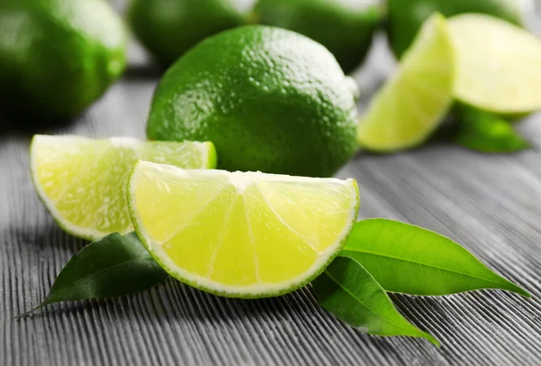 Limes and slices on wooden table, closeup — Stock Photo, Image