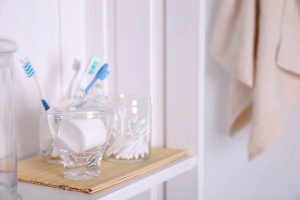 Ванная комната с полотенцем, губки и зубные щетки на светлой полке — стоковое фото