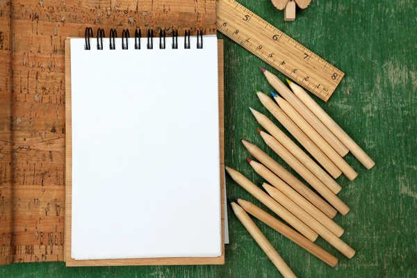 Ensemble de bureau avec cahiers, crayons de couleur et règle sur fond vert en bois — Photo