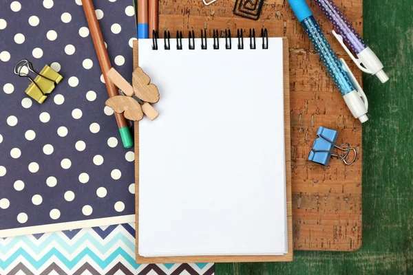 Office set with notebooks, colored pens and pencils on green wooden background