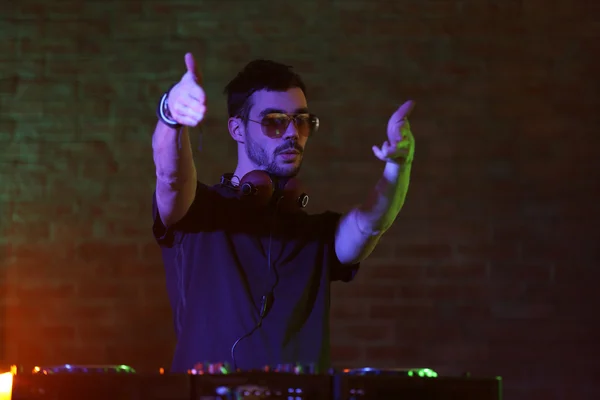 DJ tocando música en el mezclador en el fondo borroso de la pared de ladrillo — Foto de Stock