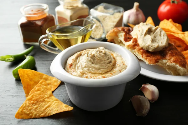Keramikskål av god hummus med chips och platt bröd på bordet — Stockfoto