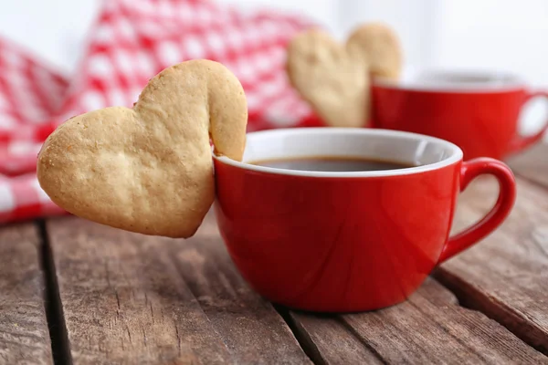 Heart shape cookie on cup of coffee on wooden table closeup — Stock Photo, Image