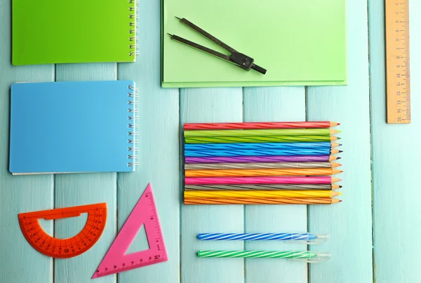 Conjunto escolar com cadernos, réguas e lápis de cor sobre fundo azul de madeira — Fotografia de Stock