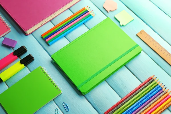 School ustawiony z notebooków i kolorowe kredki na drewniane niebieskie tło — Zdjęcie stockowe