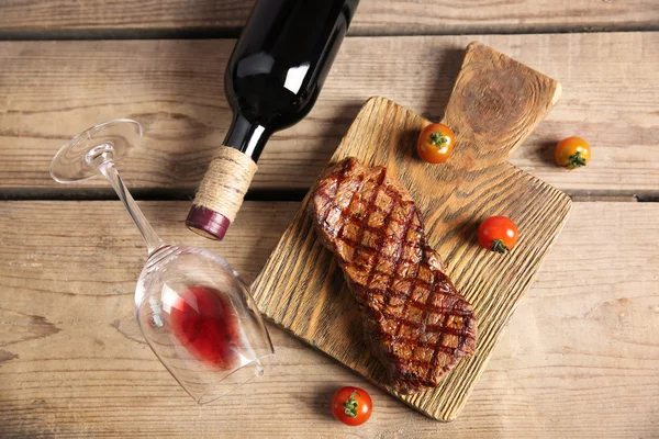 Grilled steak on cutting board with wine and cherry tomatoes, closeup — Stock Photo, Image