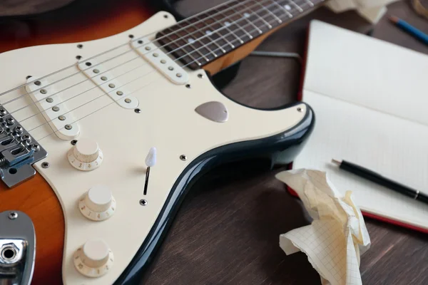 Guitar with notebook on wooden table — Stock Photo, Image