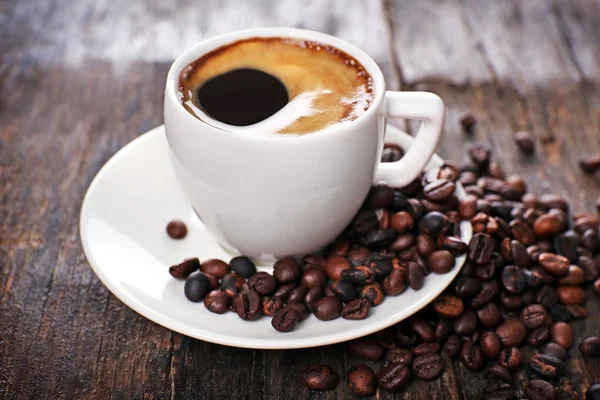 Kop warme koffie met geroosterde bonen op rustieke houten achtergrond — Stockfoto