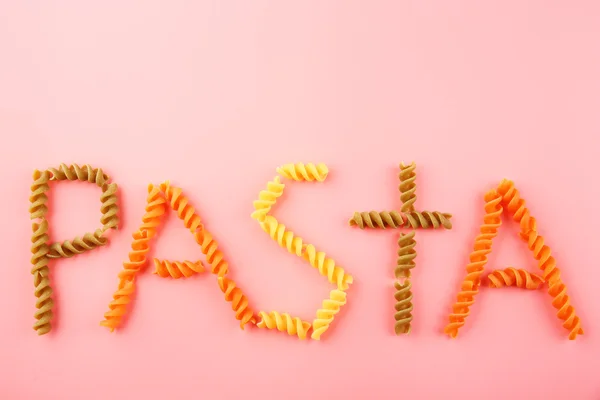 Паста-слово из разноцветных фузилли — стоковое фото