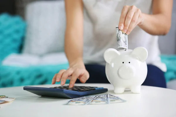 Hand putting money into piggy bank — Stock Photo, Image