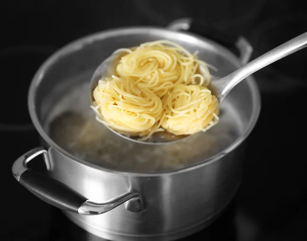 Спагетти в фильтре над кастрюлей — стоковое фото