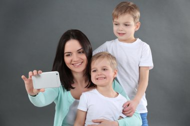 Selfie oğulları ile gri arka plan üzerinde yapma anne gülümseyerek