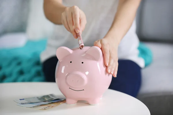 Hand putting money into piggy bank — Stock Photo, Image