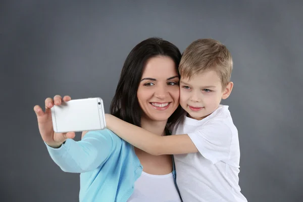 Sorrindo Mãe Fazendo Selfie Com Seu Filho Fundo Cinza — Fotografia de Stock