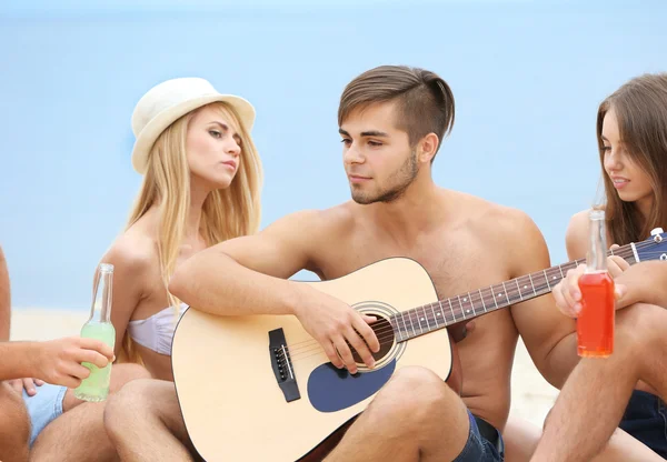 Vackra unga människor med gitarr på stranden — Stockfoto