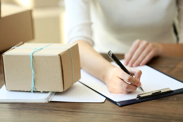 Vrouw ondertekent papieren onder percelen — Stockfoto