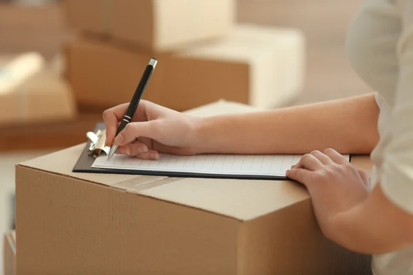 Woman signs papers among parcels — Stock Photo, Image