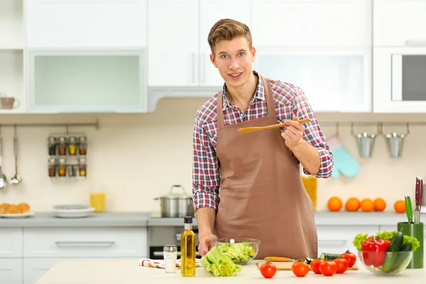 Мужчина готовит овощной салат на кухне — стоковое фото