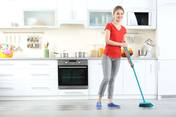 Ung kvinna tvätta golvet i kök — Stockfoto