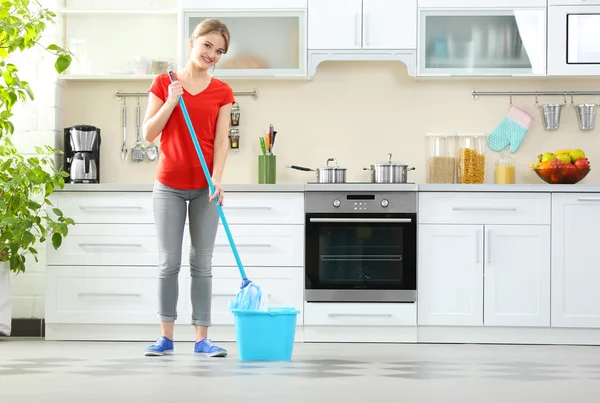 Jovem mulher lavando chão na cozinha — Fotografia de Stock