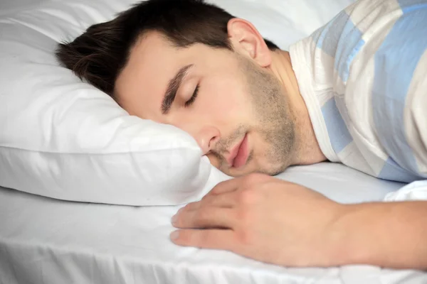 Junger Mann schläft im Bett — Stockfoto