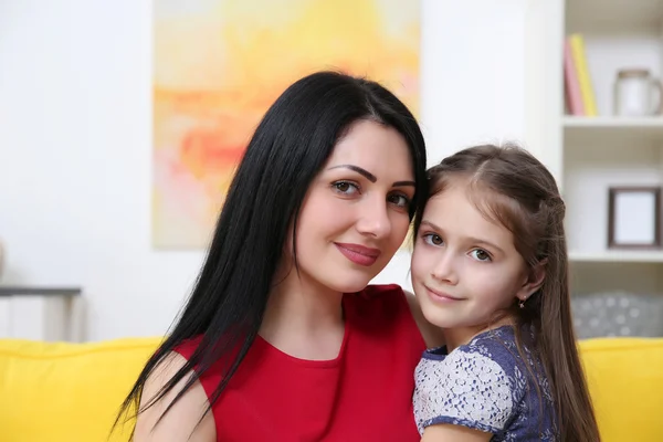 母亲和女儿坐在黄色的沙发上 — 图库照片