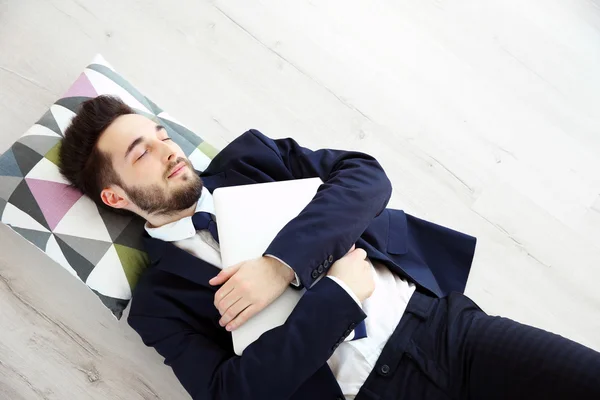 Молодой уставший бизнесмен с ноутбуком спит — стоковое фото